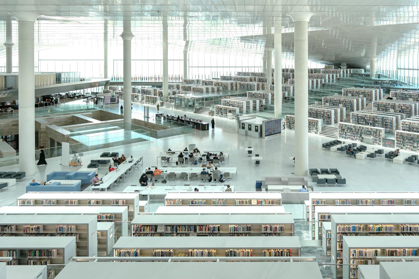 A spacious, light-filled modern library with bookshelves and students studying