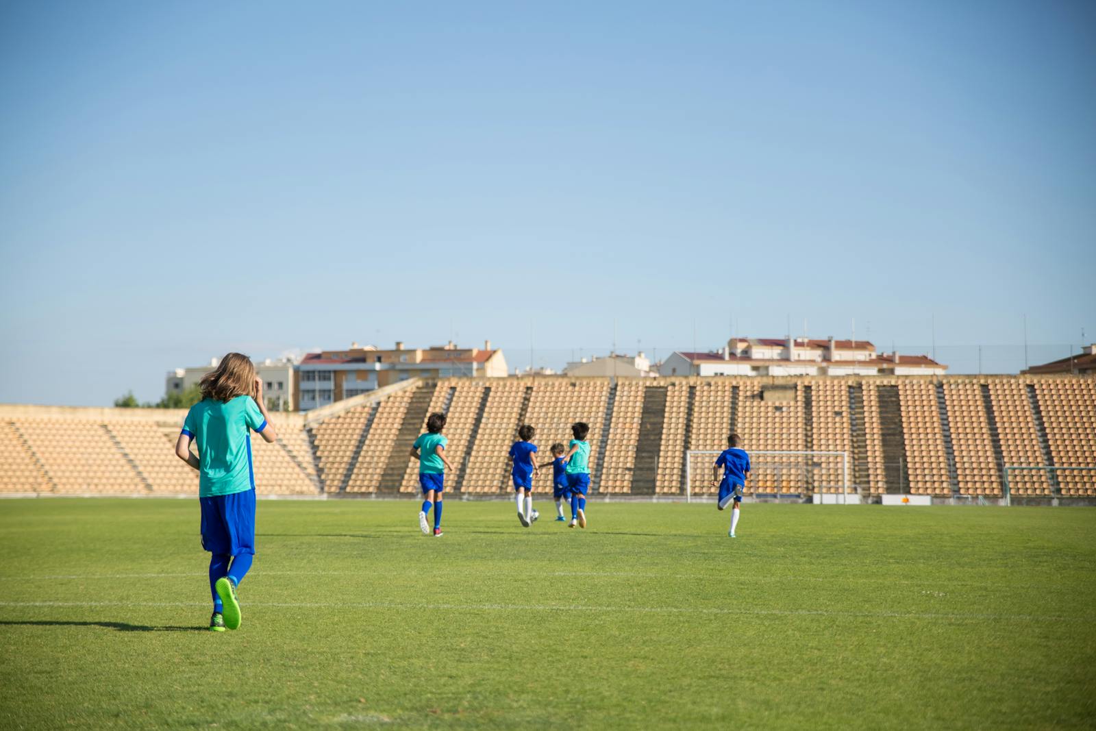 Children playing football on a sunny grass sports field